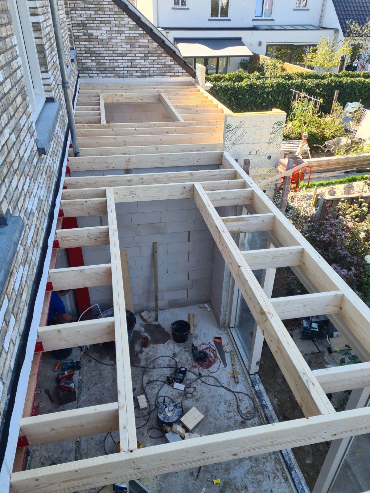 Houten balklaag in aanbouw tegen een bakstenen woning